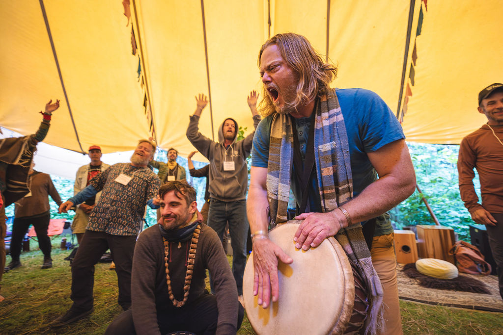 Men drumming together under a tent at the Montana retreat